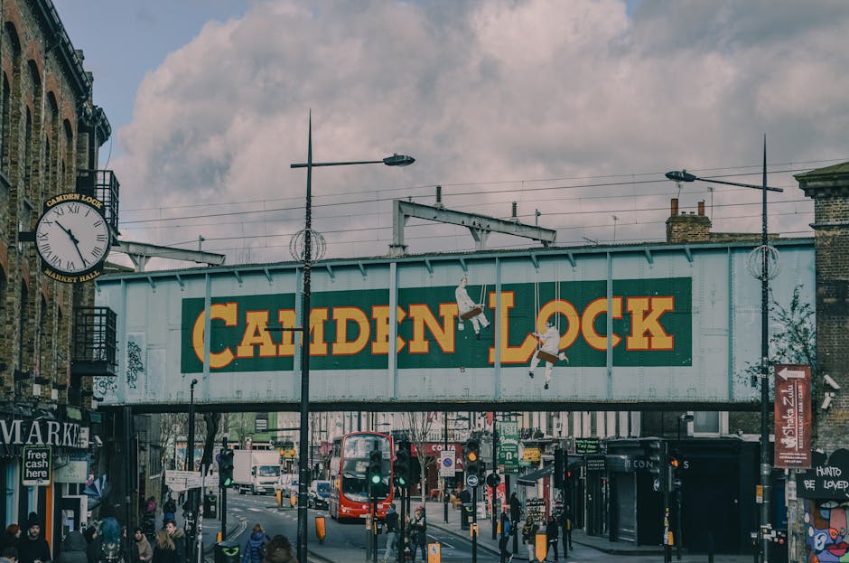 The image depicts a busy street scene with a row of commercial buildings, one of which has a large sign reading 'Cold Steel' mounted on its brick facade. The buildings are multi-storied, with various 